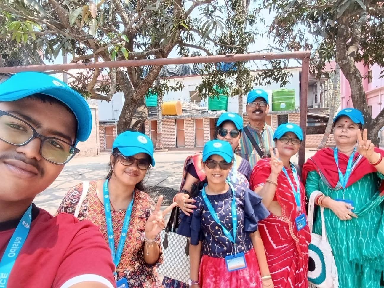 A group of travellers smiling for a selfie in matching turquoise caps